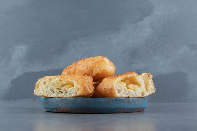 Piroshki en rodajas con patatas en placa azul.