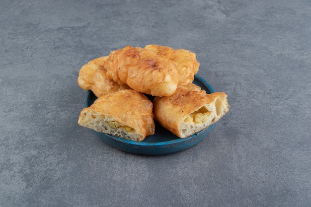 Piroshki en rodajas con patatas en placa azul.