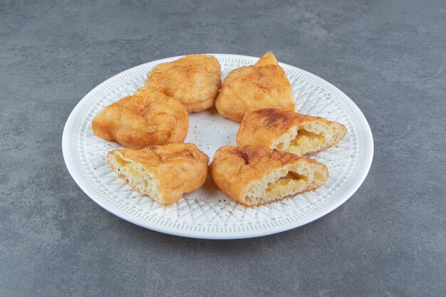 Piroshki en rodajas con patatas en un plato blanco.