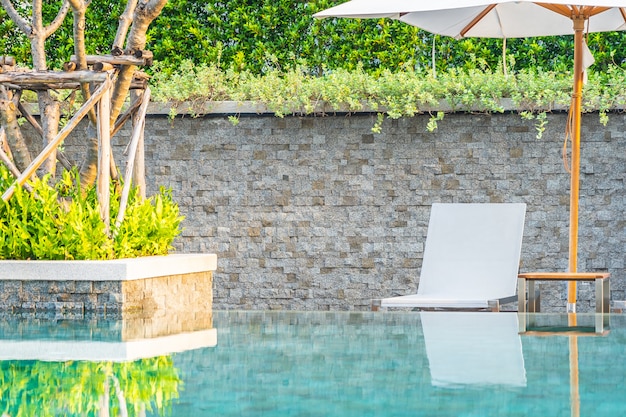 Piscina al aire libre con sillón con sombrilla y salón para viajes de placer.