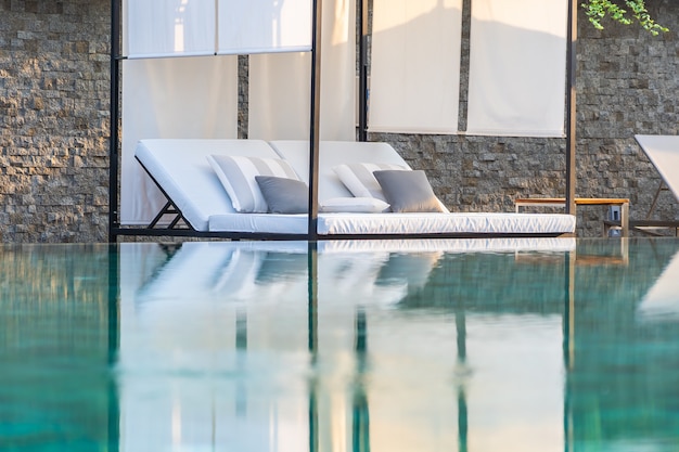 Foto gratuita piscina al aire libre con sillón con sombrilla y salón para viajes de placer.