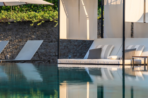 Foto gratuita piscina al aire libre con sillón con sombrilla y salón para viajes de placer.