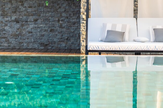 Piscina al aire libre con sillón con sombrilla y salón para viajes de placer.