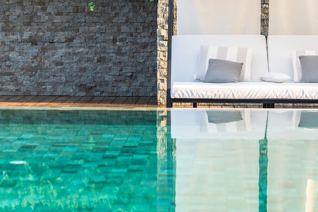 Piscina al aire libre con sillón con sombrilla y salón para viajes de placer.