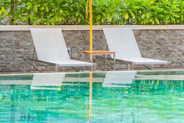 Piscina al aire libre con sillón con sombrilla y salón para viajes de placer.