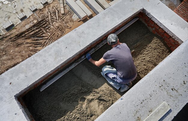 Piso de alisado de trabajador masculino en el sitio de construcción