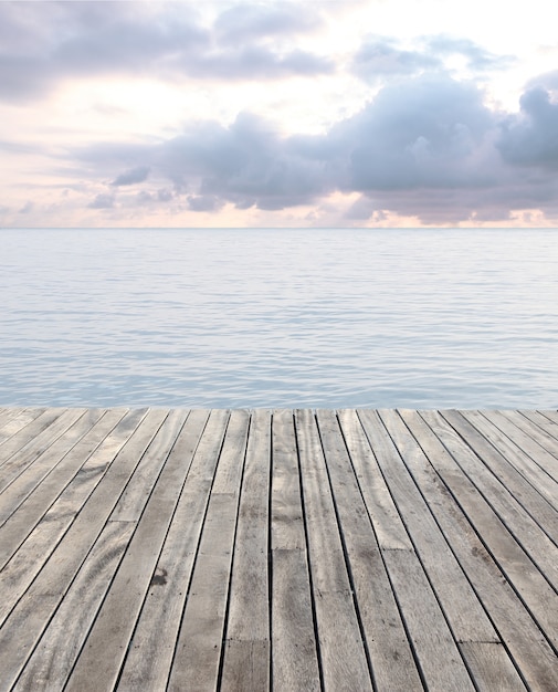 piso de madera y el mar azul con olas y cielo nublado