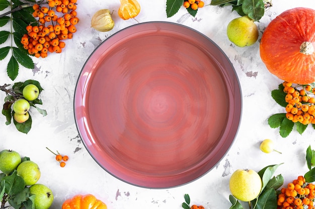 Piso de otoño yacía con calabazas, manzanas, peras y bayas de serbal sobre un fondo de piedra blanca