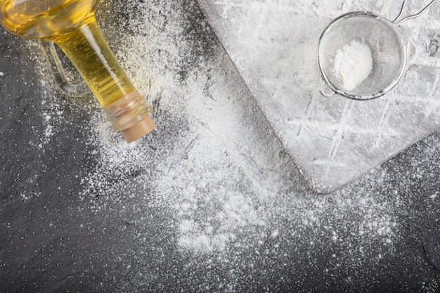 Piso de trigo fresco derramado sobre tabla de madera con vaso de aceite