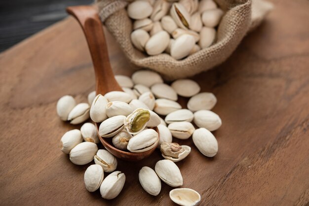 Pistachos en una cuchara de madera. Saco con pistachos sobre una mesa de madera.