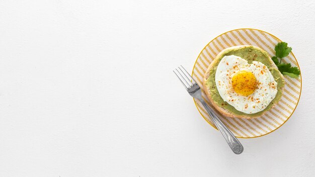 Pita laicos plana con aguacate y huevo frito en un plato con espacio de copia