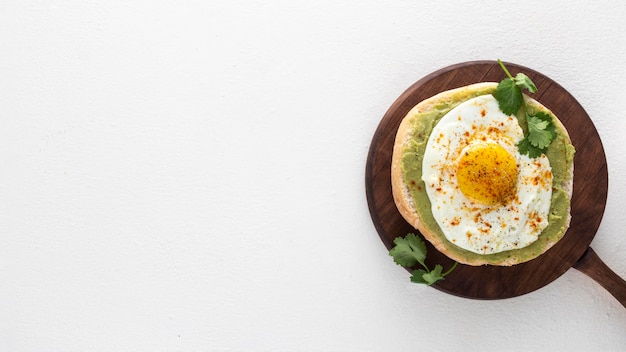 Pita laicos plana con extensión de aguacate y huevo frito con espacio de copia en la tabla de cortar