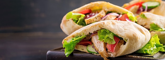 Pita rellena de pollo, tomate y lechuga en la mesa de madera. Cocina del Medio Oriente.