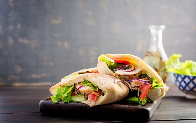 Pita rellena de pollo, tomate y lechuga en la mesa de madera. Cocina del Medio Oriente.