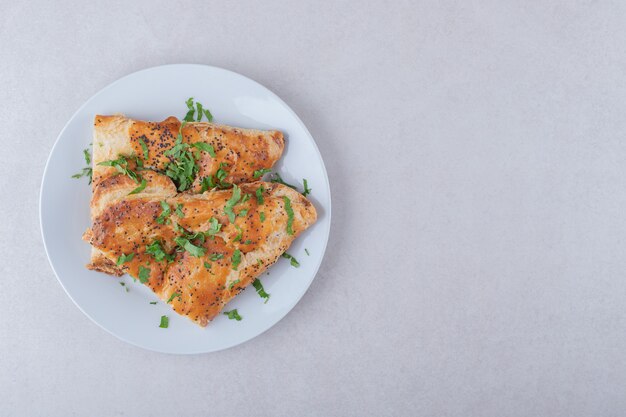 Pita de sésamo con perejil picado en un plato sobre una mesa de mármol.