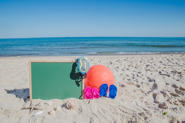 Pizarra y accesorios de playa en la arena