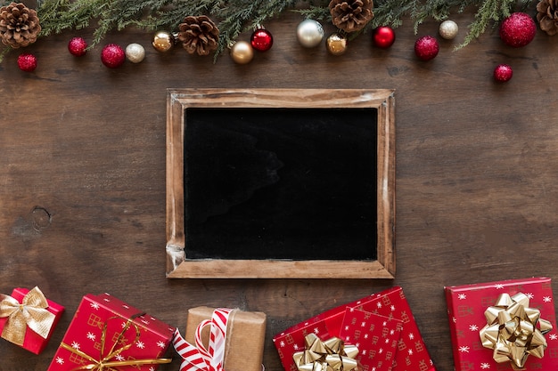 Pizarra con cajas de regalo brillantes en mesa