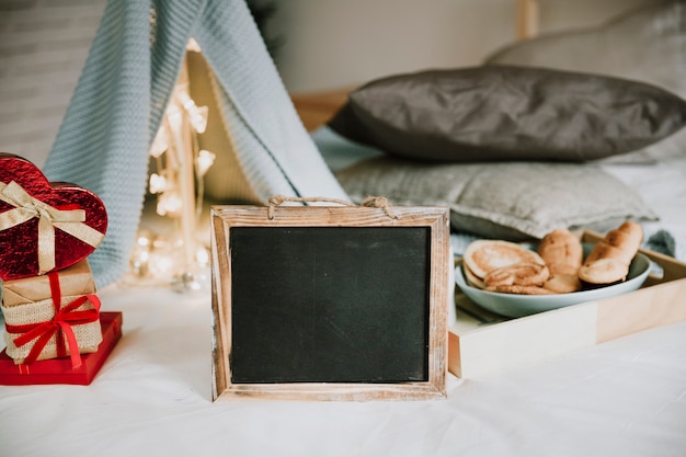 Foto gratuita pizarra cerca del desayuno y montón de regalos