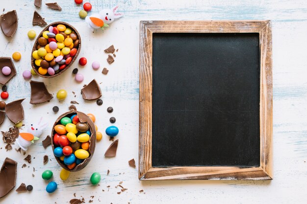 Pizarra cerca de dulces y conejos de Pascua