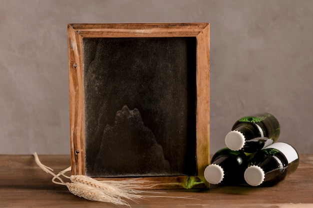 Pizarra junto a tres botellas de cerveza en mesa de madera