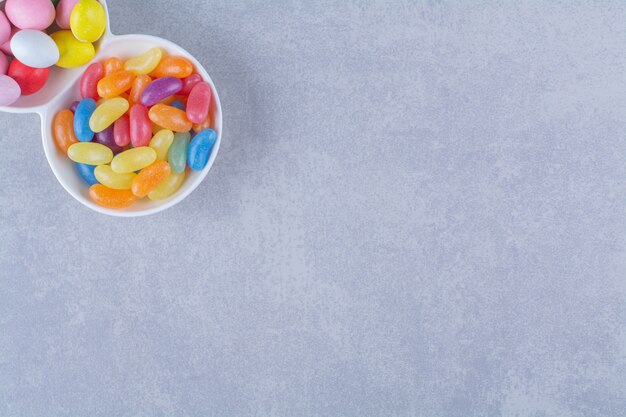 Una pizarra llena de coloridos caramelos de frijol sobre superficie gris