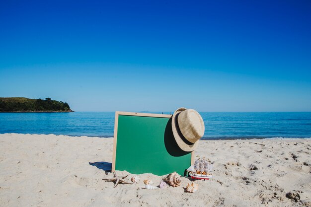 Pizarra y sombrero de paja en la playa