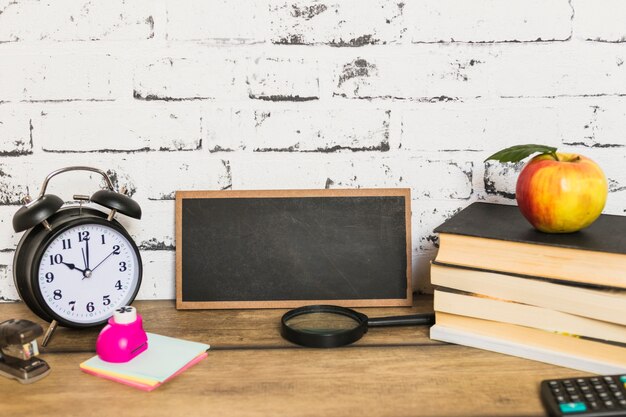 Pizarra y útiles escolares con manzana encima de libros