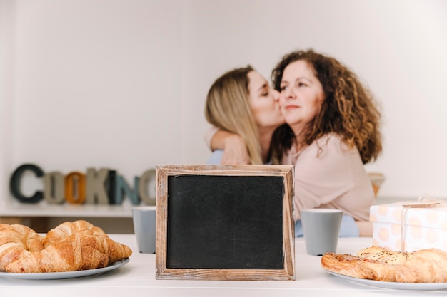 Pizarra vacía cerca de la hija besando a la madre