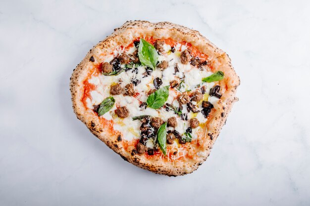 Pizza al horno con carne picada, mozarella, salsa de tomate y albahaca.