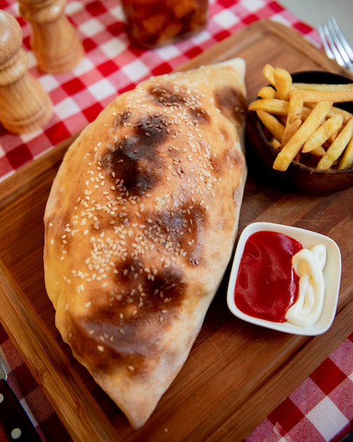 Foto gratuita pizza calzone con papas fritas y salsa de tomate