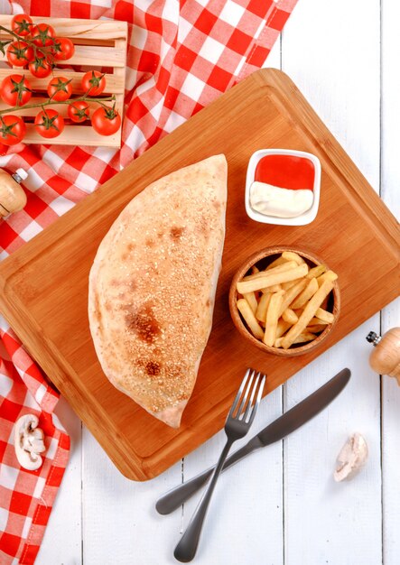 Pizza calzone con papas fritas en el tablero de madera