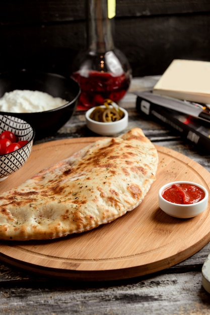 Foto gratuita pizza calzone sobre tabla de madera