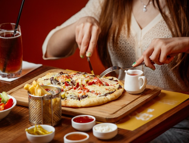 Pizza de carne con queso y verduras sobre tabla de madera