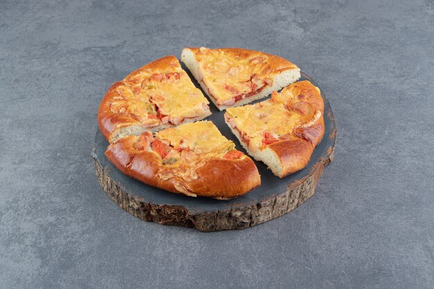 Pizza casera en rodajas sobre pieza de madera.