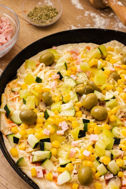 Pizza cruda de alto ángulo con ingredientes en sartén