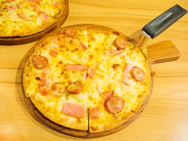 Pizza y cuchara elevadora en bandeja de madera.
