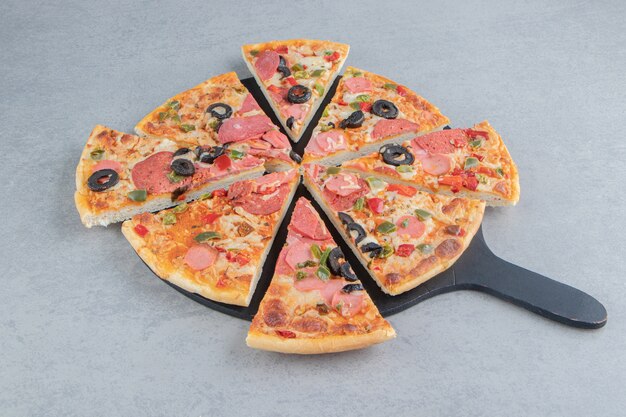 Pizza cuidadosamente rebanada en una tabla de mármol