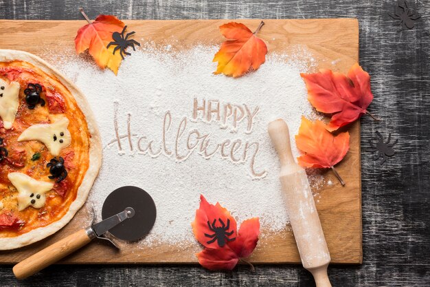 Pizza de Halloween con hojas sobre tabla de madera