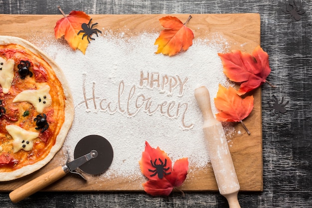 Pizza de Halloween con hojas sobre tabla de madera