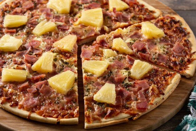 Pizza hawaiana con piña y queso sobre mesa de madera