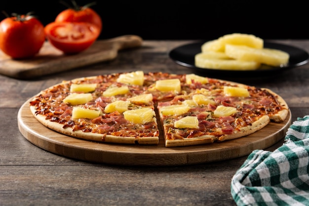 Pizza hawaiana con piña y queso sobre mesa de madera