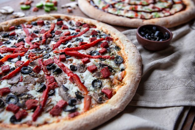 Pizza de ingredientes mixtos con pimiento rojo picado y aceitunas negras