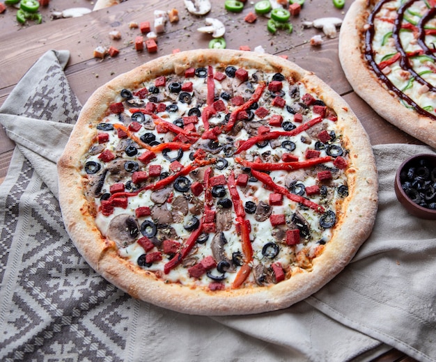 Pizza de ingredientes mixtos con pimiento rojo picado y aceitunas negras