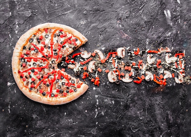 Una pizza de ingredientes mixtos con productos aislados en la piedra.