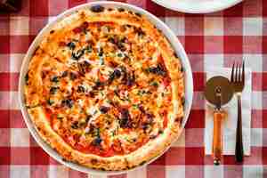 Foto gratuita pizza italiana casera con tomates secos queso mozzarella alcaparras y especias en el mantel vista superior con espacio para copiar texto cubiertos sobre la mesa sobre la mesa