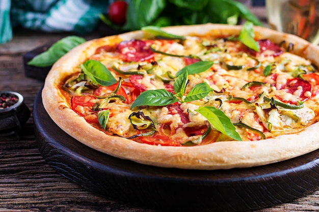 Pizza italiana con pollo, salami, calabacín, tomates y hierbas.