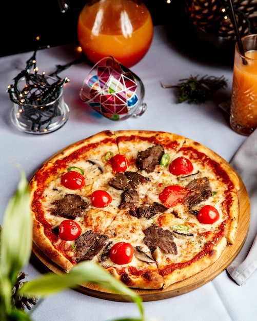 Foto gratuita pizza mixta con trozos de carne y tomate