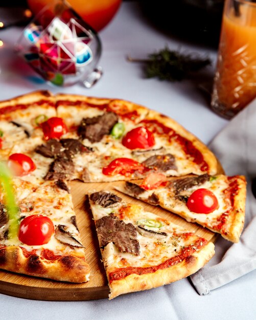 Pizza mixta con trozos de carne y tomate.