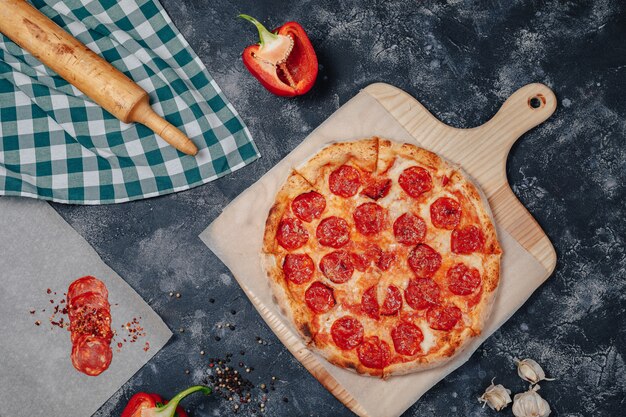 Pizza napolitana deliciosa en una pizarra con varios ingredientes, espacio libre para texto