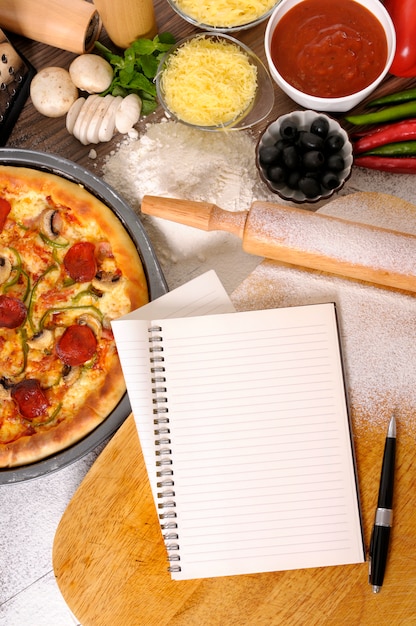 Foto gratuita pizza pepperoni con libro de cocina